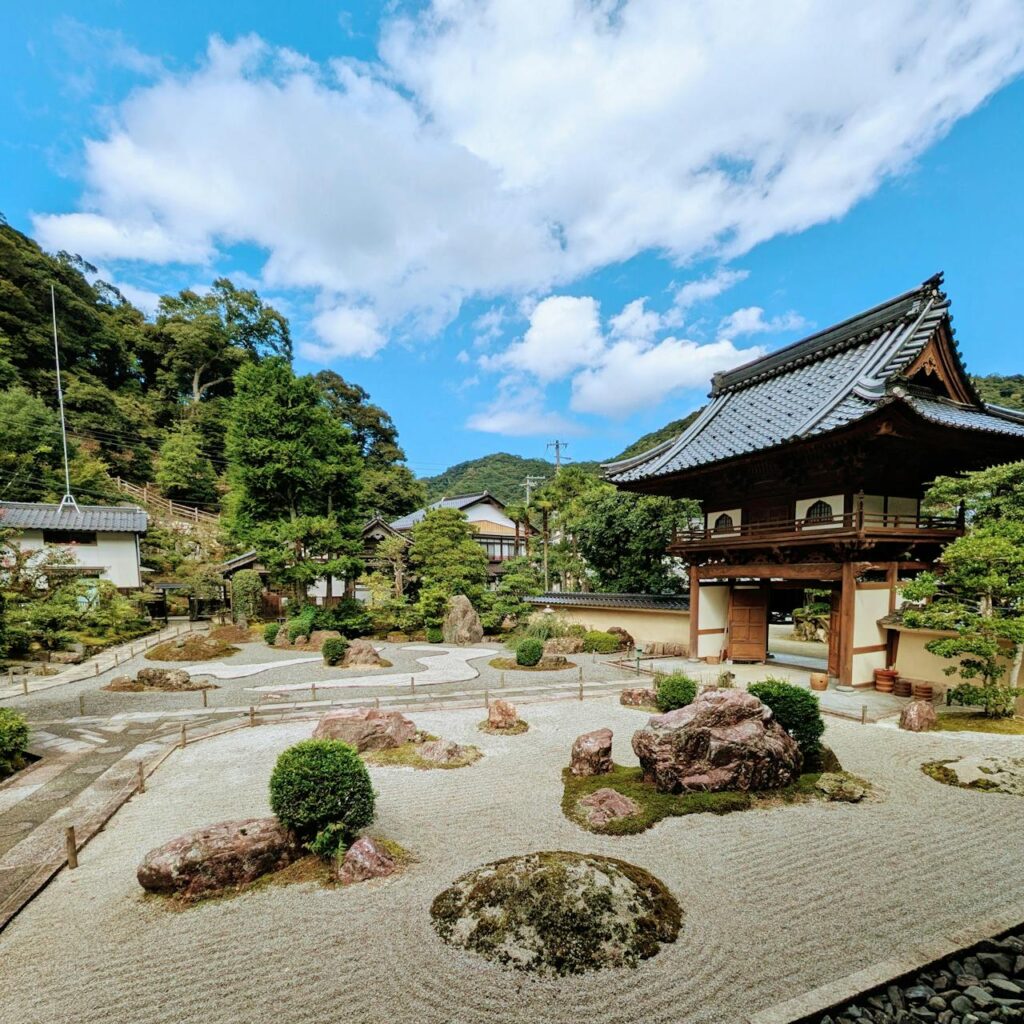 Japán száraz kert kövekkel, formára metszett növényekkel.